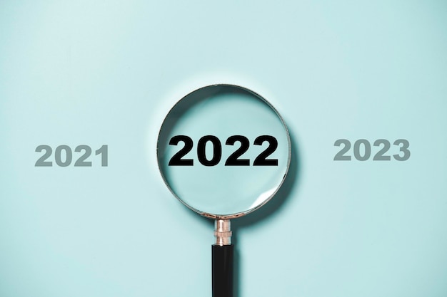 2022 year inside of magnifier glass on blue background for focus on target of new business of starting new year concept.