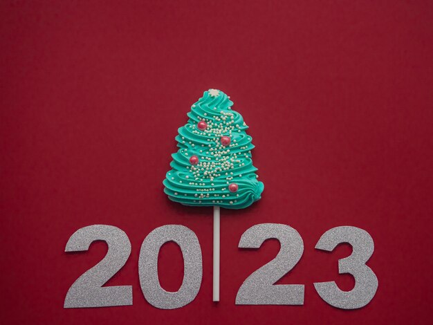 2023 and blue candy in the form of a Christmas tree on a red background