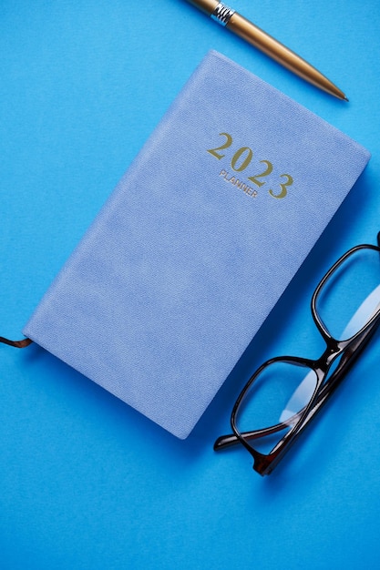 2023 dagboek brillen en potlood op blauwe achtergrond