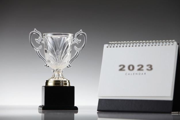 2023 desktop calendar and trophy on gray background
