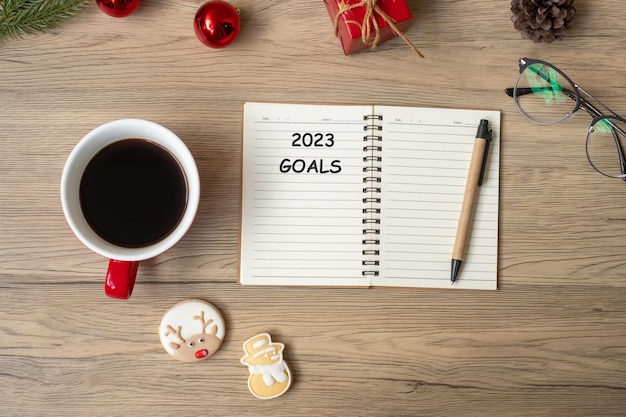 2023 doel met notebook zwarte koffiekopje kerstkoekjes en pen op houten tafel xmas happy new year resolutie to do list strategie en plan concept