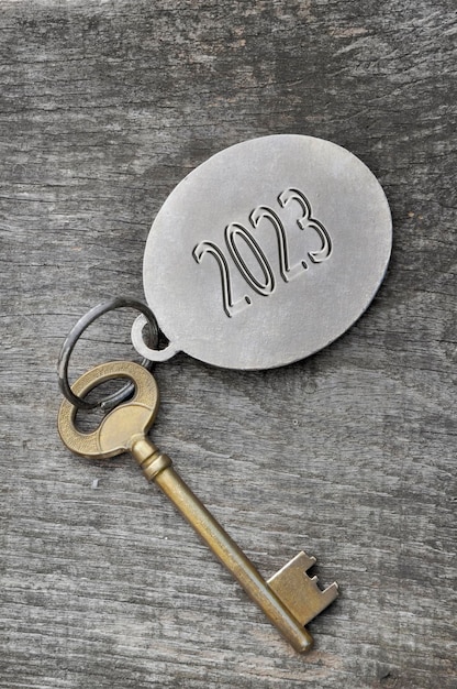 2023 engraved on a ring of an old golden key on rustic wooden