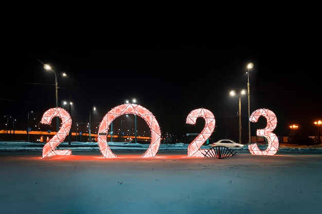 어두운 밤 배경의 눈 위의 2023 인물 장식 인물은 새해 축하를 위해 도시 광장을 장식합니다.