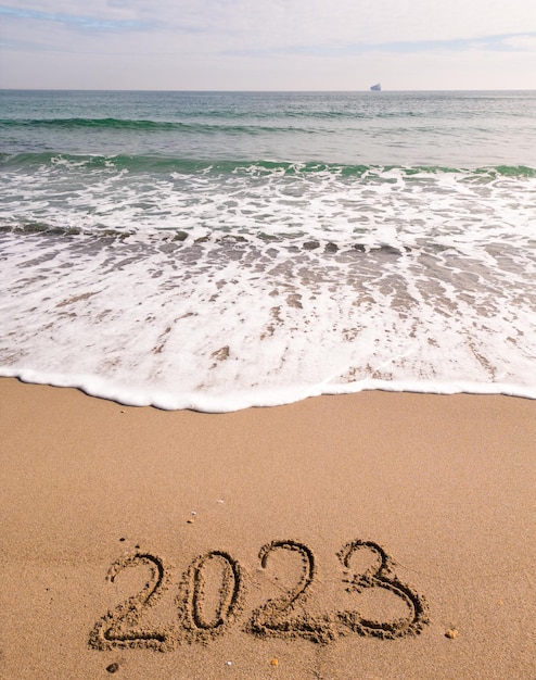 2023 jaar geschreven op zandstrand zee op zonnige dag