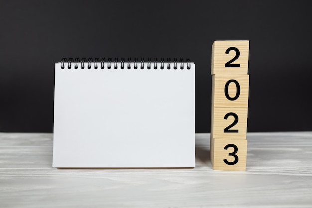 Foto 2023 kalender mockuptekst 2023 op houten kubussen plaats voor uw tekst in notitieblok kalenderindeling nieuwjaar opstartconcept kalendertabel 2023 voor planning en herinneringsorganisator op een houten tafel