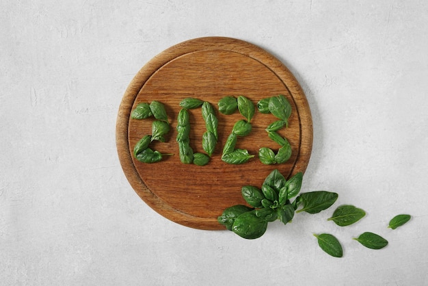 木製のまな板にほうれん草の葉で作られた2023年の健康と健康的なライフスタイルの決議明けましておめでとうございます