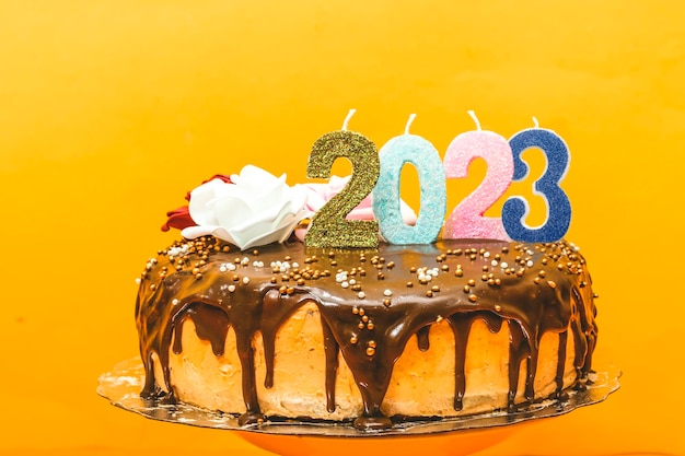 2023 new year birthday cake chocolate and cream decorated with numbers candle and flowers