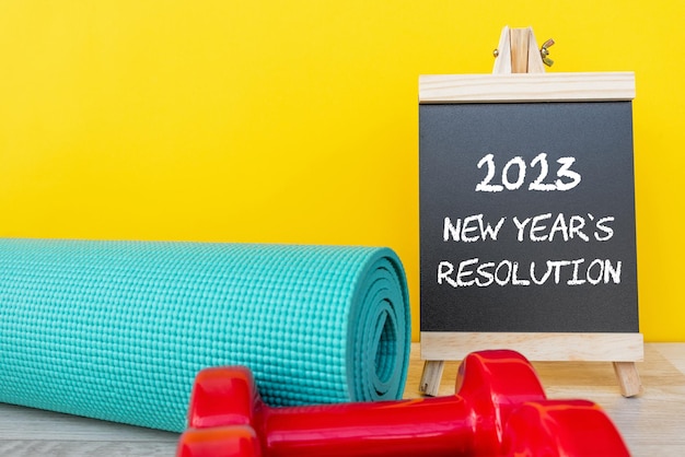 2023 New Year's Resolution with yoga mat and dumbbell fitness concept