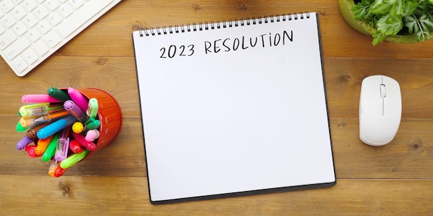 2023 resolution on blank notebook paper on wood background 2023 new year mock up template flat lay