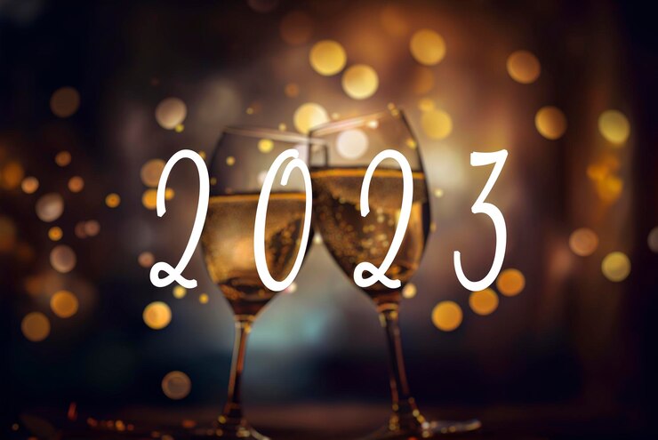 Photo 2023 text and two champagne glasses with a blurred golden bokeh lights in background