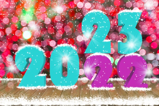 2023 Text on wood table top with snow and decorative light bokeh background