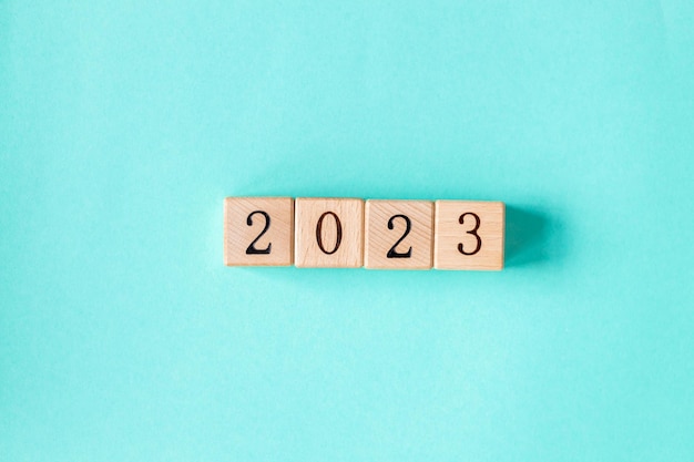 2023 word is made of wooden blocks on the turquoise background Happy New Year