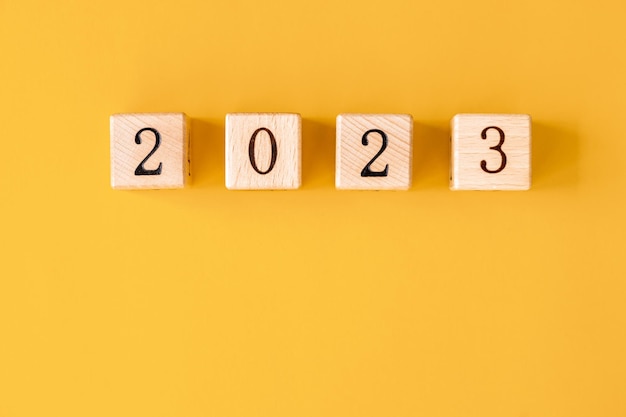 2023 word is made of wooden blocks on the yellow background Happy New Year