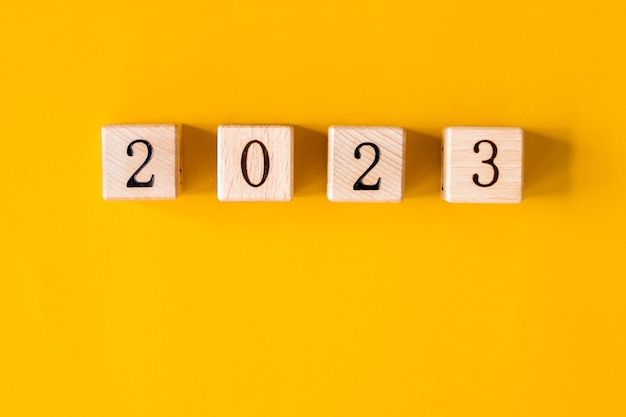 2023 word is made of wooden blocks on the yellow background Happy New Year