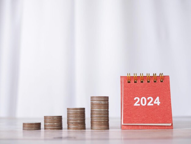 2024 desk calendar and stack of coins The concept of saving money Financial Investment and Business growing in new year 2024