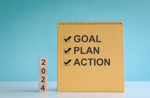 2024 goal plan and action words on wood block and calendar