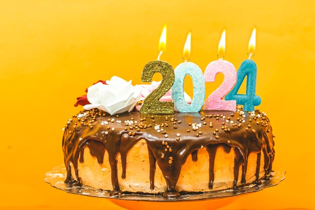 Новогодний торт на день рождения 2024, шоколадно-сливочный, украшенный цифрами, свечами и цветами