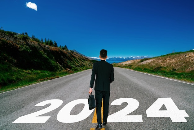 2024 new year journey and future vision concept businessman traveling on highway road leading forward to happy new year celebration in beginning of 2024 for bliss and successful start