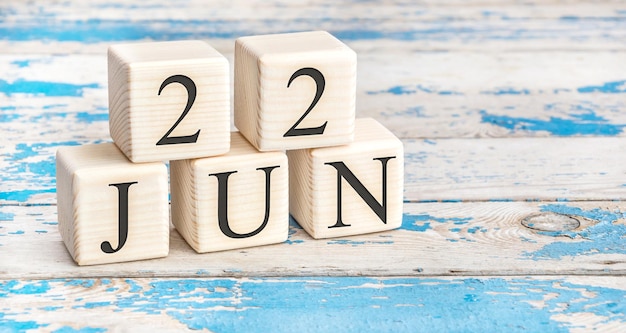 22 juni Houten kubussen met datum van 22 juni op oude blauwe houten achtergrond