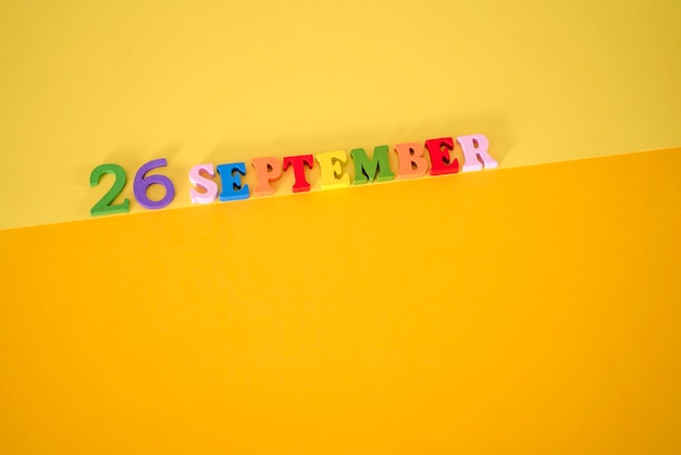 Foto 23 september op een gele en papieren achtergrond met houten letters en cijfers in verschillende kleuren