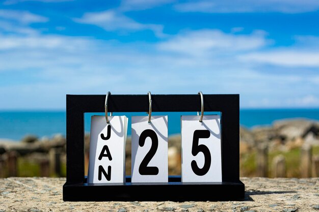 Foto 25 januari kalender datum tekst op houten frame met wazige achtergrond van de oceaan kalender concept