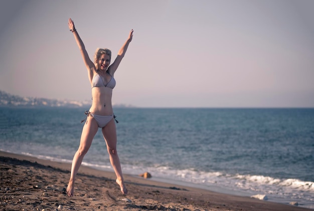 27 year old blonde woman in bikini on the beach Girl jumping on the beach