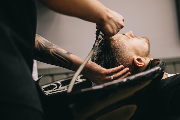 Foto 27022020 odessa, oekraïne het proces van het wassen van het haar op het hoofd van de klant in een mannelijke kapperszaak met shampoo