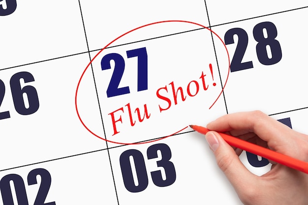 27th day of the month Hand writing text FLU SHOT and circling the calendar date