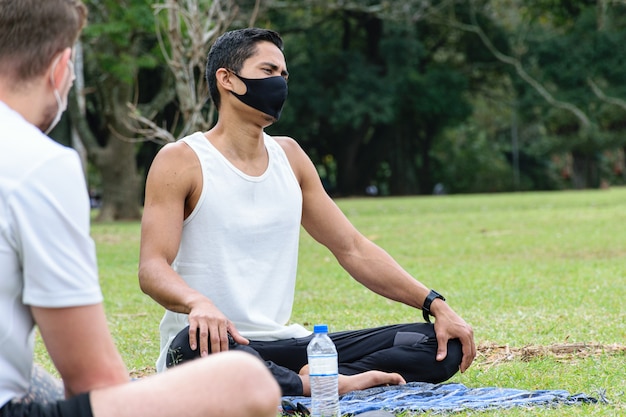 28 year old Brazilian young man, yoga teacher, sitting on the lawn next to a bottle of water.