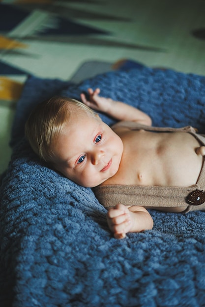 Foto un bambino di due mesi giace in pantaloni a maglia su una coperta grigia.