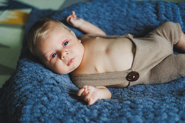 A 2monthold baby is lying in knitted pants on a gray blanket Clothes for babies