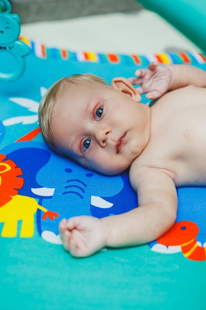 A 2monthold baby lies on a developmental mat and plays with toys While playing the child gets to know the world and learns shapes and colors Child development