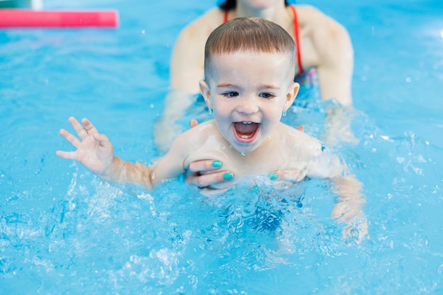 2歳の男の子がコーチと一緒にプールで泳ぎを学ぶ 子供向け水泳教室 子供向けスイミングスクール 子供向け水泳教育コース