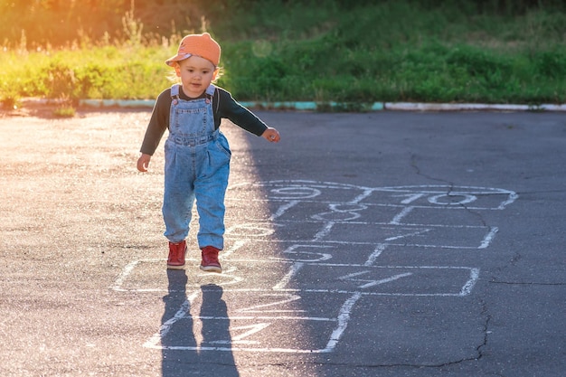 A 2yearold kid plays hopscotch on the playground during sunset