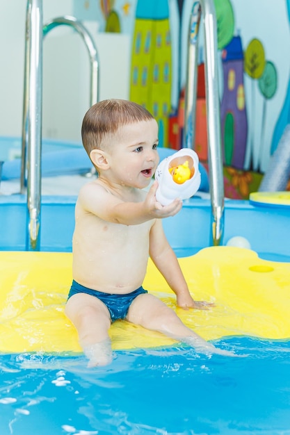 A 2yearold little boy is learning to swim in the pool Swimming lessons for young children Swimming school for children