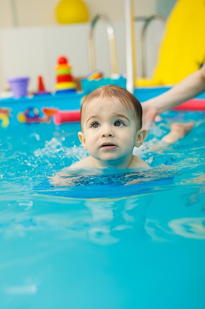 A 2yearold little boy learns to swim in a pool with a coach Swimming lessons for children