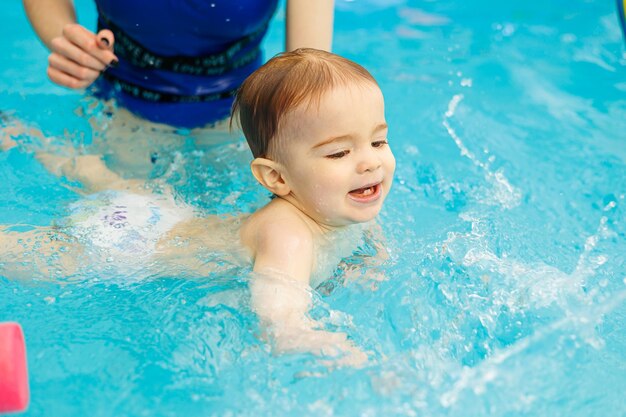 コーチと一緒にプールで泳ぐことを学ぶ 2 歳の男の子 子供のための水泳レッスン