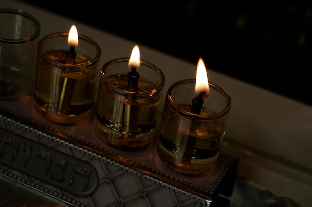 3 aangestoken kaarsen in de menorah op een donkere achtergrond