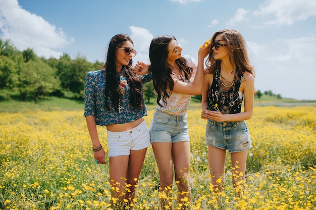 3 beautiful hippie girl in a field of yellow flowers