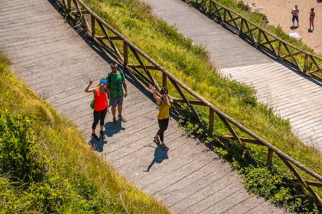 3 friends going down to Orio beach seen from above on a June summer afternoon