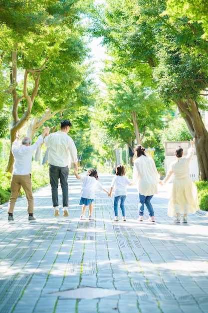 緑豊かな通りで手をつないで3世代家族