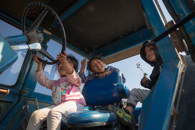 3 Rural play happy children playing and exploring the field from the top of a tractor