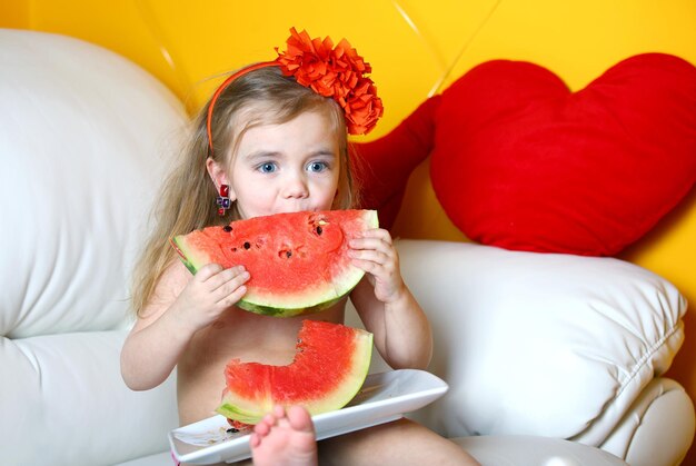 A 3 year old girl eats a watermelon