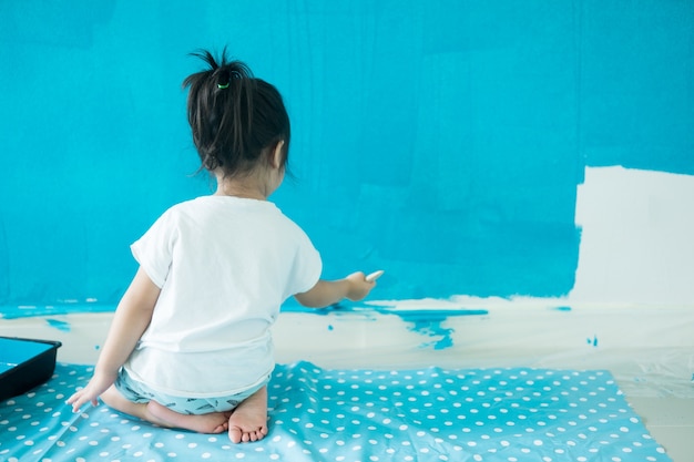 3 years old girl painting the wall at home.