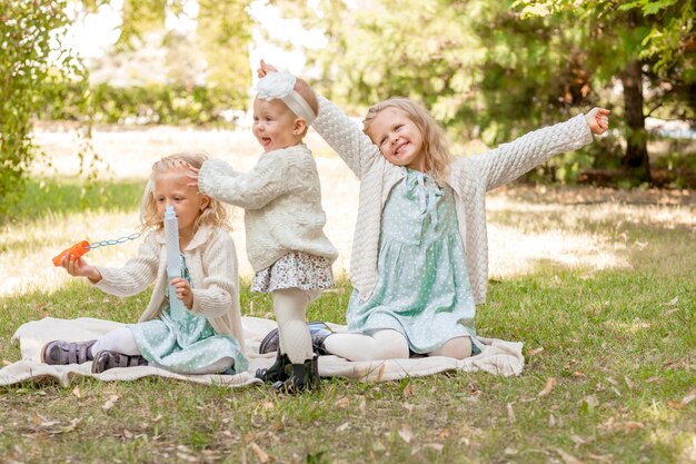 Foto 3 zussen op een picknick spelen met zeepbellen zomervakantie 3 blonde meisjes
