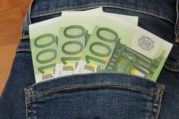 300 euros sticking out of the jeans pocket. Three paper bills of 100 euros each. 