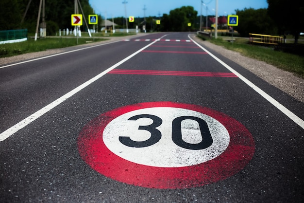 아스팔트 도로에 30km / h 속도 제한 표지판이 그려져 있습니다.