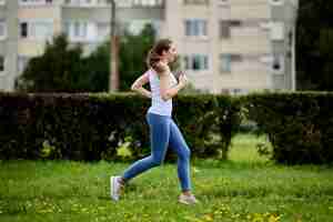 Photo 30s woman is running in city park on summer morning