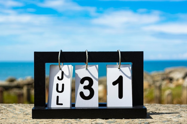 Foto 31 juli kalender datum tekst op houten frame met wazige achtergrond van de oceaan kalender concept