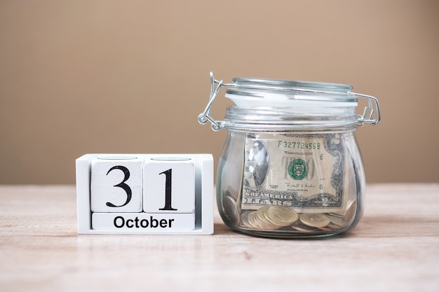 31 October of calendar wooden and money in glass jar on table, world saving day